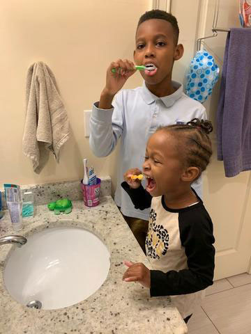 photo of african american boy and girl using the two minute turtle timer while brushing teeth at their bathroom sink