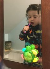 Load image into Gallery viewer, Girl brushing teeth watching her green turtle-shaped toothbrush timer stuck to bathroom mirror.  Lit-up color flippers
