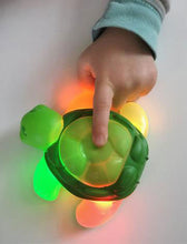 Load image into Gallery viewer, child pressing a green toothbrush timer shaped like a turtle
