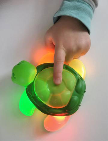 child pressing a green toothbrush timer shaped like a turtle